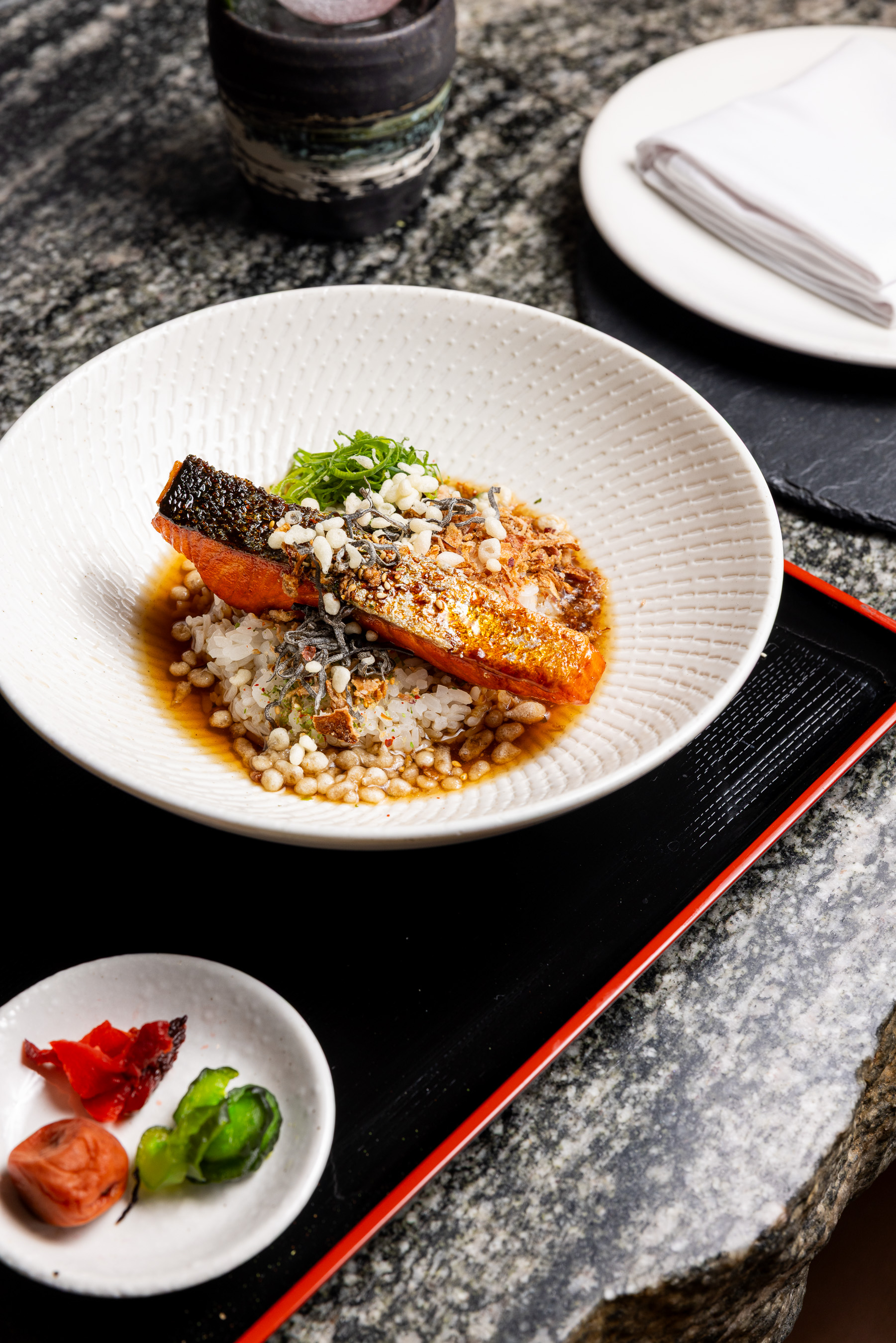 Crispy-skinned king salmon over rice in broth with rice crackers, served with Japanese pickles