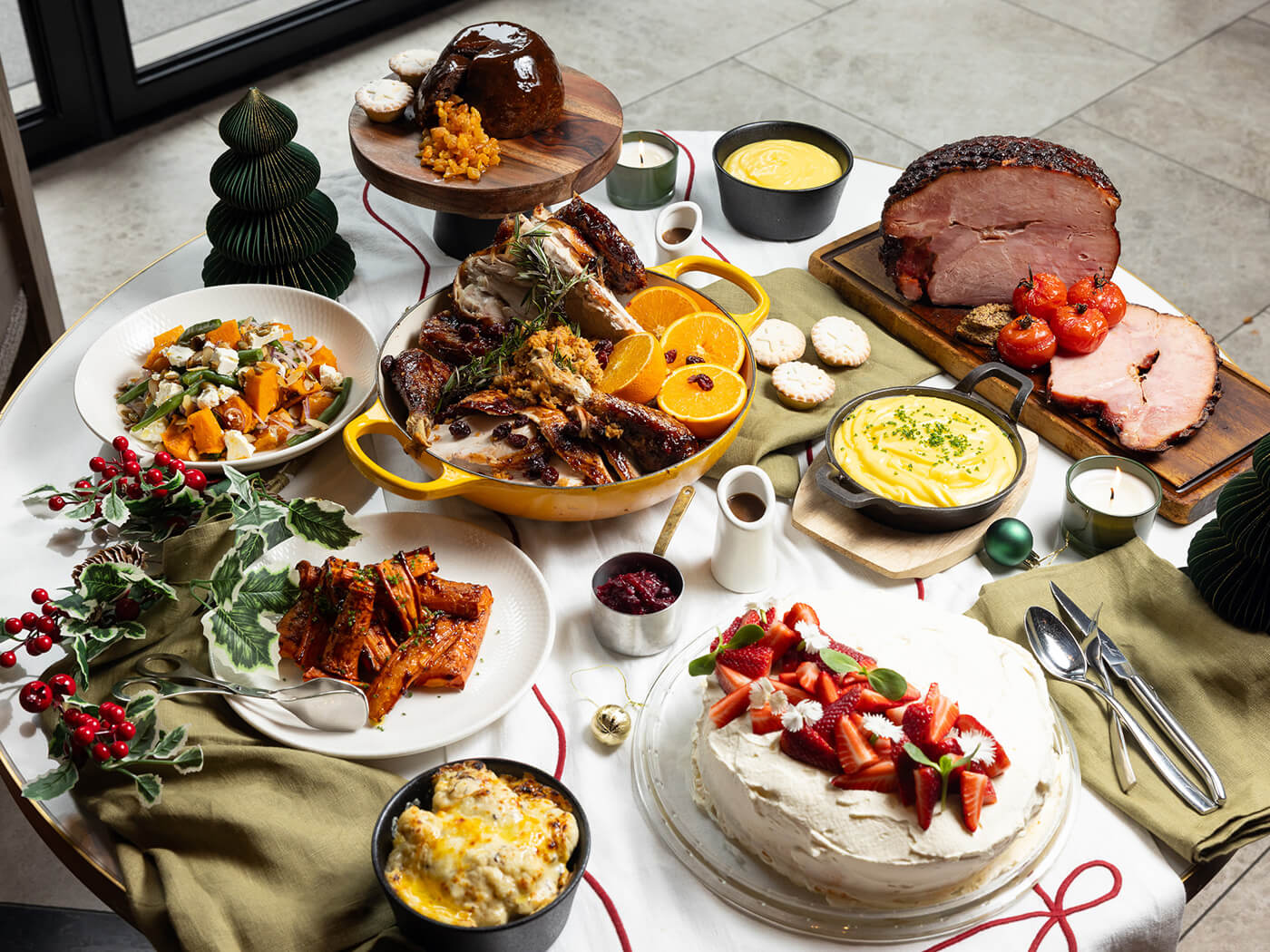 A full Christmas table from The Grill with roast turkey, glazed ham, seasonal sides and a strawberry pavlova.