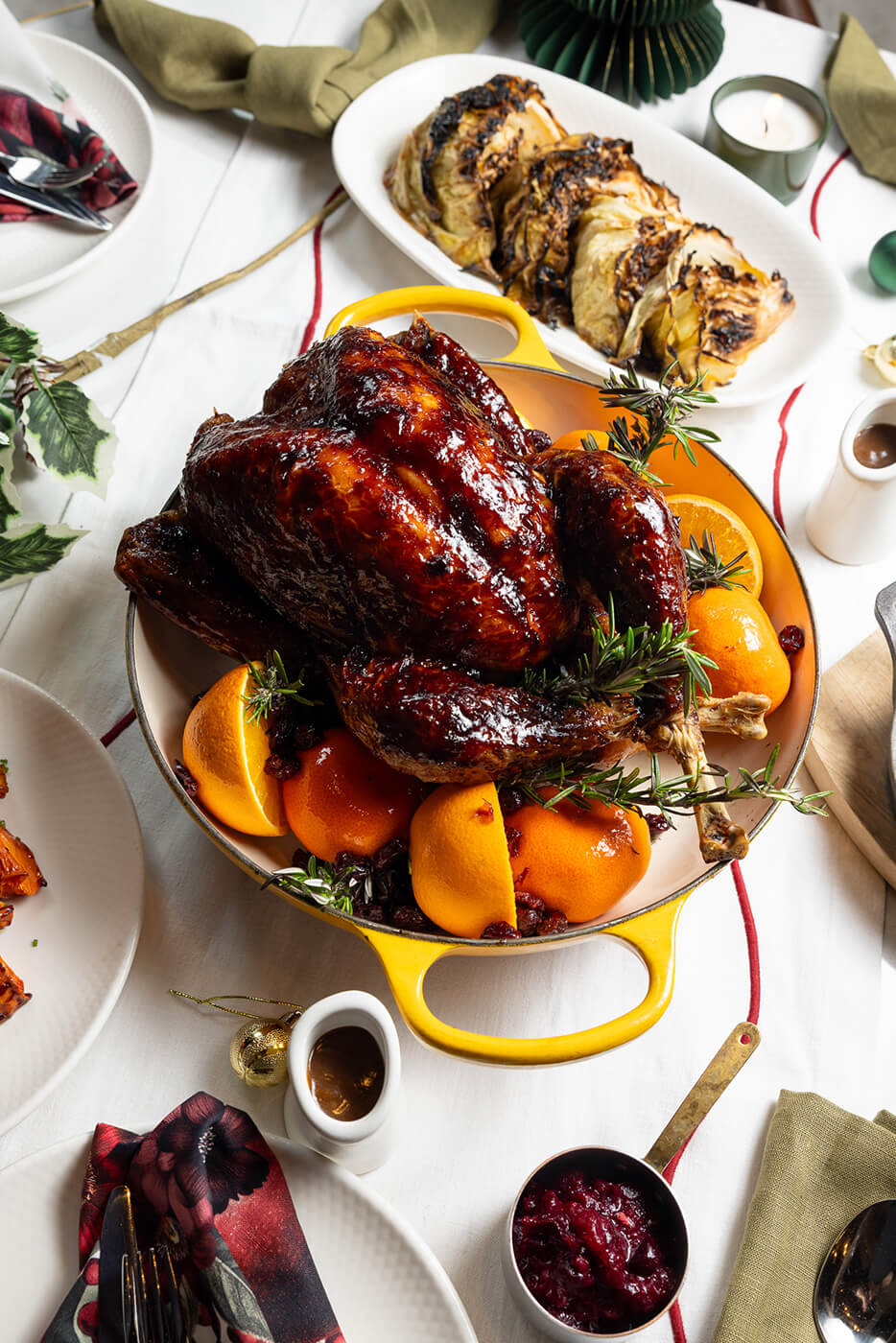 Whole roast turkey glazed and served in a casserole dish with oranges and rosemary.
