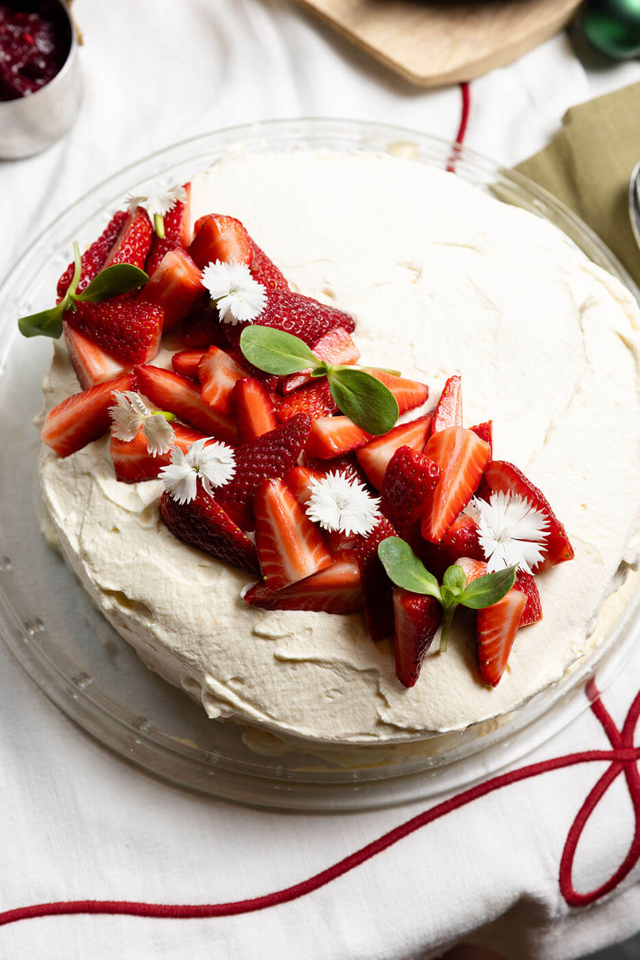 Strawberry pavlova topped with cream, fresh strawberries and edible flowers.