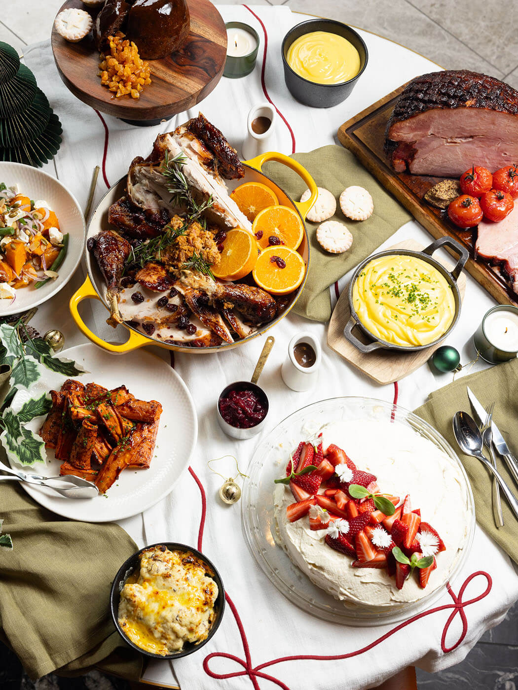A full Christmas table from The Grill with roast turkey, glazed ham, seasonal sides and a strawberry pavlova.