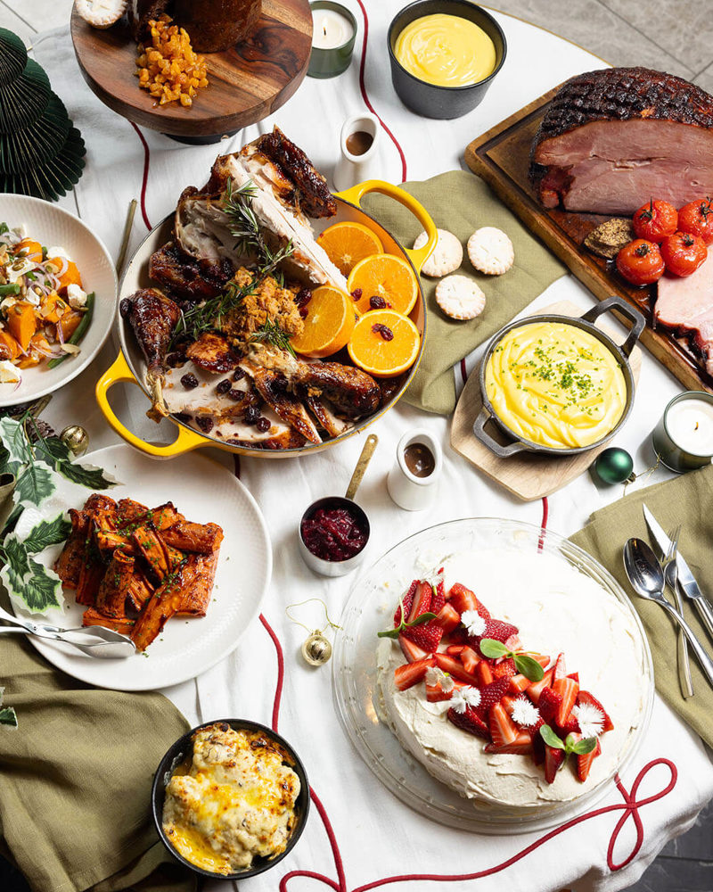A full Christmas table from The Grill with roast turkey, glazed ham, seasonal sides and a strawberry pavlova.