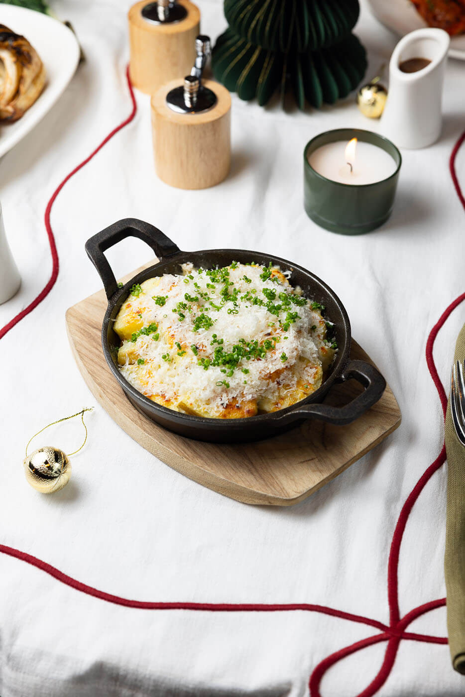Creamy potato gratin topped with cheese and chives in a cast iron dish.